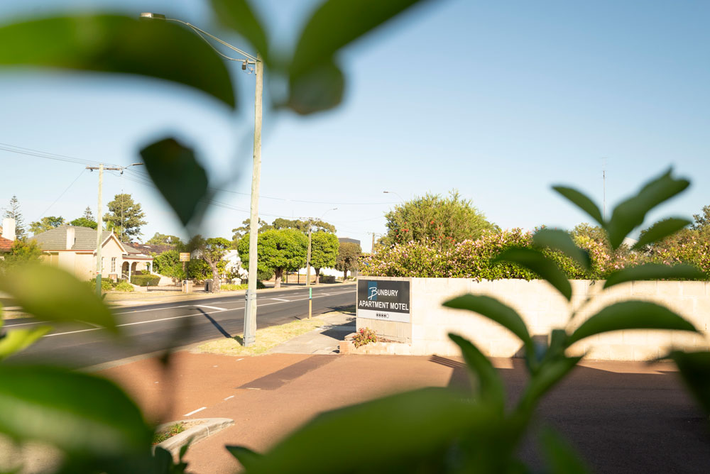 Bunbury Apartment Motel drive-in entrance surrounded by lush trees